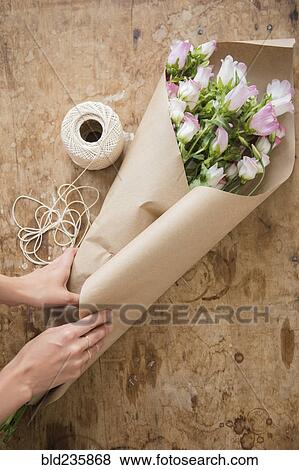 Hands of Caucasian woman wrapping bouquet in brown paper View Large Photo Image Stock Photo - Hands of Caucasian woman wrapping bouquet in brown paper. Fotosearch