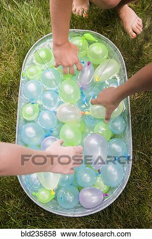 Hands of girls reach for water balloons in tub View Large Photo Image Stock Photo - Hands of girls reach for water balloons in tub. Fotosearch