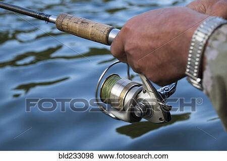 Stock Photo - Hands of Mari man holding fishing rod in river. Fotosearch