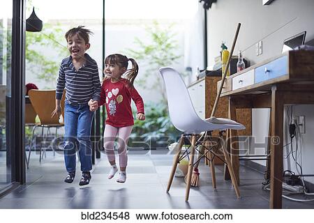 Stock Photo - Hispanic brother and sister holding hands and jumping. Fotosearch