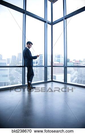 Hispanic businessman leaning on window texting on cell phone View Large Photo Image Stock Image - Hispanic businessman leaning on window texting on cell phone. Fotosearch