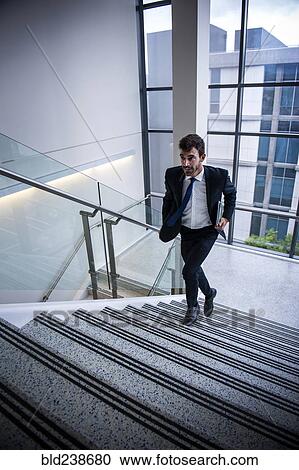 Stock Image - Hispanic businessman running on staircase. Fotosearch