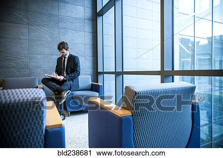 Stock Image - Hispanic businessman writing on notepad in office lounge. Fotosearch