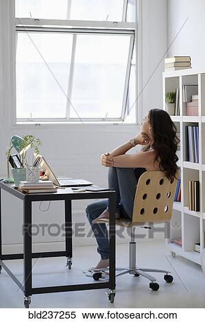 Stock Photography - Hispanic businesswoman daydreaming in office. Fotosearch