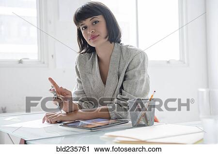 Stock Image - Hispanic businesswoman in office with digital tablet. Fotosearch