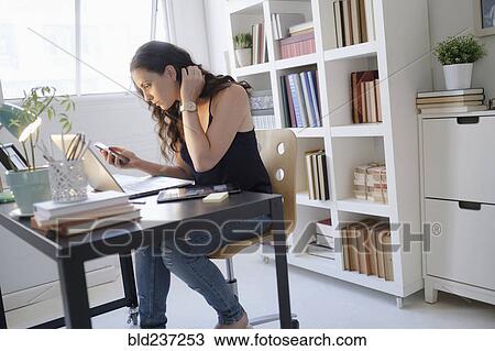 Stock Image - Hispanic businesswoman using technology in office. Fotosearch