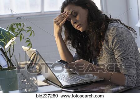 Stock Image - Hispanic businesswoman using technology in office. Fotosearch