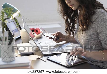 Stock Photo - Hispanic businesswoman using technology in office. Fotosearch