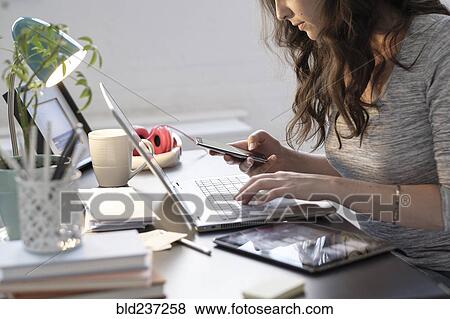 Stock Photo - Hispanic businesswoman using technology in office. Fotosearch