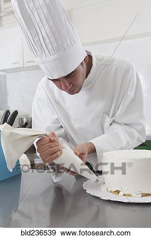 Stock Photo - Hispanic chef decorating cake. Fotosearch