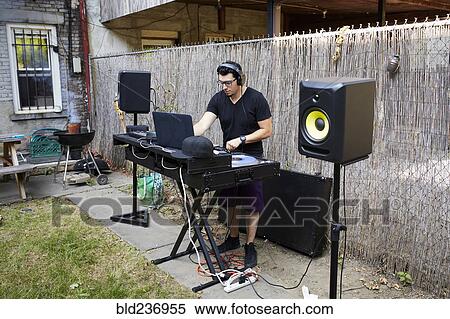 Stock Photography - Hispanic dj playing music in backyard. Fotosearch