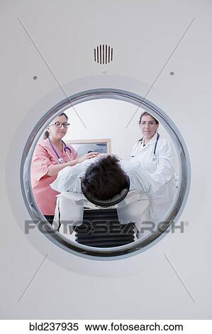 Stock Photography - Hispanic doctor and nurse comforting patient at scanner. Fotosearch