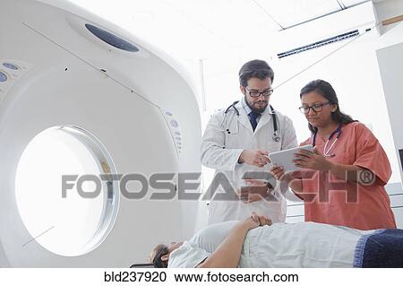 Stock Image - Hispanic doctor and nurse using digital tablet near scanner. Fotosearch