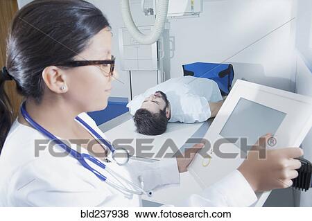 Stock Photo - Hispanic doctor at control panel of x-ray machine. Fotosearch