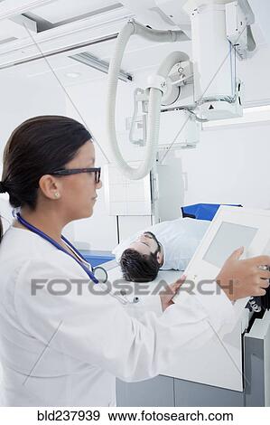 Stock Photo - Hispanic doctor at control panel of x-ray machine. Fotosearch