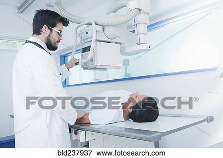 Stock Photo - Hispanic doctor comforting patient at x-ray machine. Fotosearch