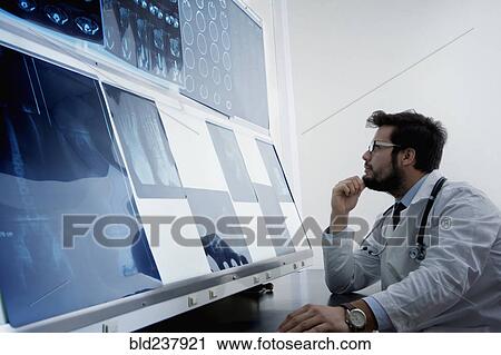 Stock Image - Hispanic doctor examining x-rays. Fotosearch