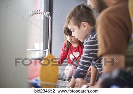 Stock Image - Hispanic family washing dishes at sink. Fotosearch