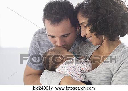 Stock Photo - Hispanic father kissing baby daughter. Fotosearch