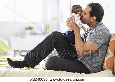 Hispanic father kissing baby daughter on cheek View Large Photo Image Stock Photography - Hispanic father kissing baby daughter on cheek. Fotosearch