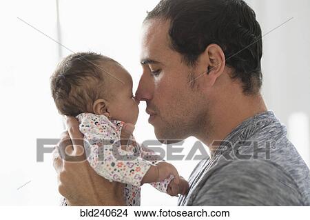 Picture - Hispanic father rubbing noses with baby daughter. Fotosearch