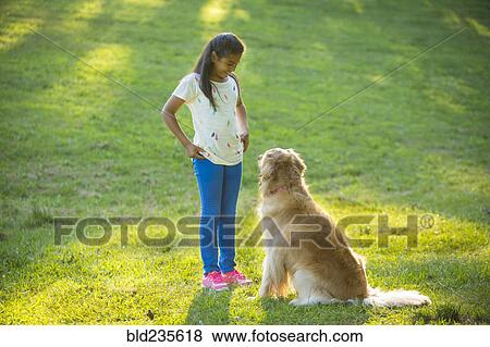 Stock Photo - Hispanic girl training dog on hill. Fotosearch
