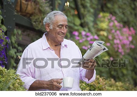 Hispanic man drinking coffee and reading newspaper in flower garden View Large Photo Image Stock Photograph - Hispanic man drinking coffee and reading newspaper in flower garden. Fotosearch