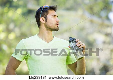 Stock Image - Hispanic man drinking smoothie outdoors. Fotosearch
