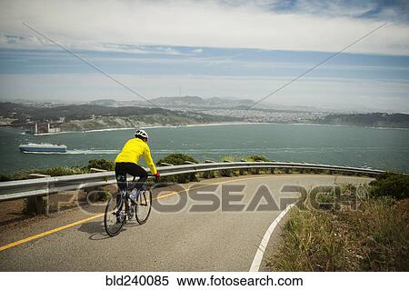 Hispanic man riding bicycle on waterfront road View Large Photo Image Stock Photography - Hispanic man riding bicycle on waterfront road. Fotosearch