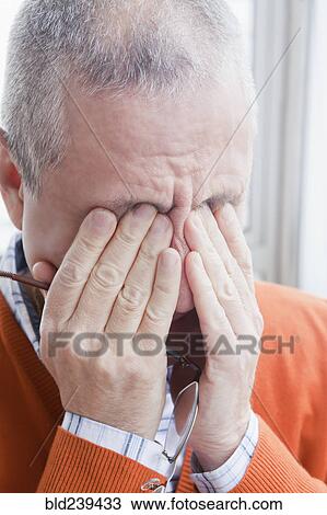 Stock Image - Hispanic man rubbing eyes. Fotosearch