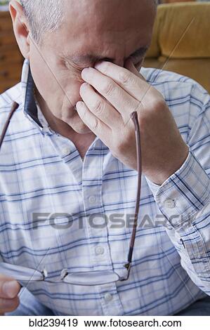 Stock Photo - Hispanic man rubbing eyes. Fotosearch
