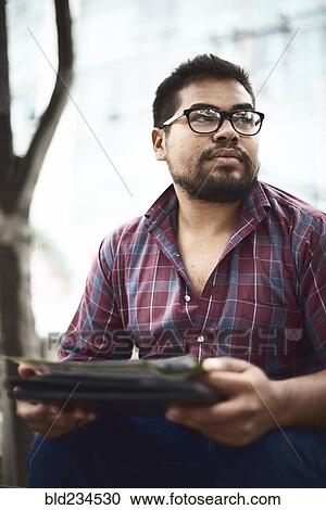 Stock Image - Hispanic man sitting outdoors. Fotosearch