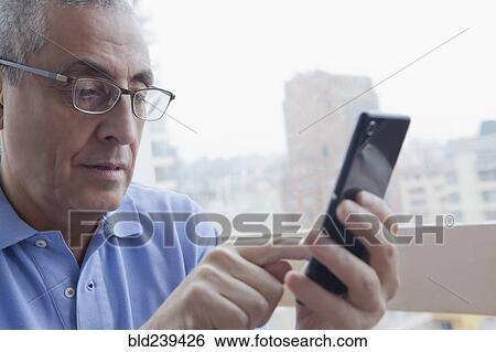 Stock Photograph - Hispanic man texting on cell phone. Fotosearch