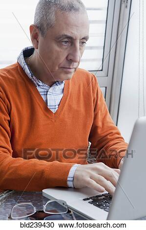 Stock Image - Hispanic man using laptop. Fotosearch