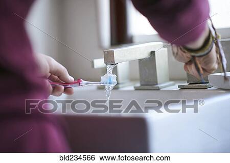 Hispanic man wetting toothbrush in sink View Large Photo Image Stock Photograph - Hispanic man wetting toothbrush in sink. Fotosearch