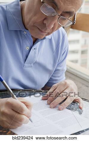 Hispanic man writing on paperwork View Large Photo Image Picture - Hispanic man writing on paperwork. Fotosearch