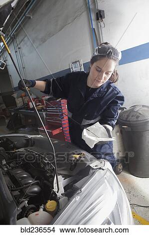 Hispanic mechanic checking oil in car engine View Large Photo Image Picture - Hispanic mechanic checking oil in car engine. Fotosearch
