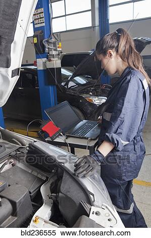 Stock Photography - Hispanic mechanic diagnosing car engine with laptop. Fotosearch