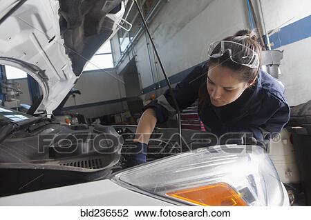 Stock Image - Hispanic mechanic repairing car engine. Fotosearch