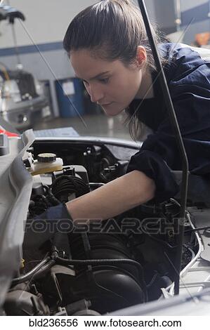Stock Photograph - Hispanic mechanic repairing car engine. Fotosearch