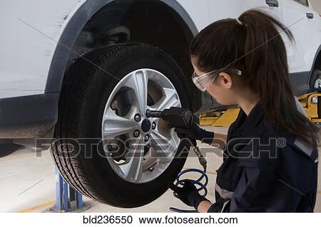 Stock Image - Hispanic mechanic repairing car wheel. Fotosearch