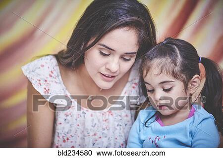 Stock Image - Hispanic mother and daughter looking down. Fotosearch