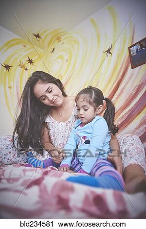 Hispanic mother and daughter on bed looking down View Large Photo Image Stock Image - Hispanic mother and daughter on bed looking down. Fotosearch