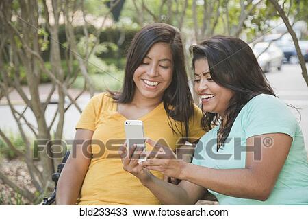 Stock Image - Hispanic mother and daughter posing for cell phone selfie. Fotosearch