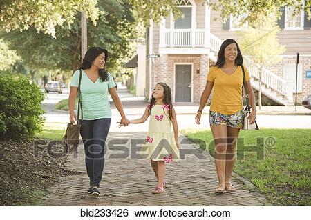 Stock Photograph - Hispanic mother and daughters walking in park. Fotosearch