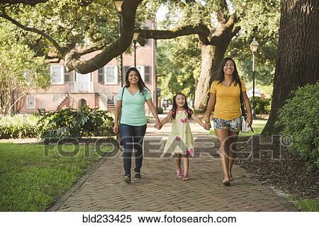 Stock Photography - Hispanic mother and daughters walking in park. Fotosearch