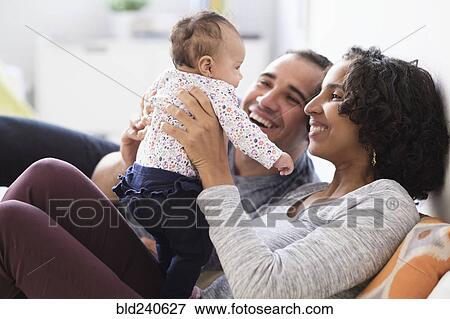 Stock Photo - Hispanic mother and father playing with baby daughter. Fotosearch