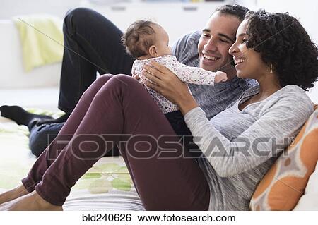 Stock Photograph - Hispanic mother and father playing with baby daughter. Fotosearch