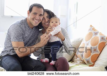 Stock Photo - Hispanic mother and father posing with baby daughter. Fotosearch