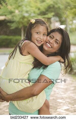 Stock Photo - Hispanic mother carrying and hugging daughter. Fotosearch